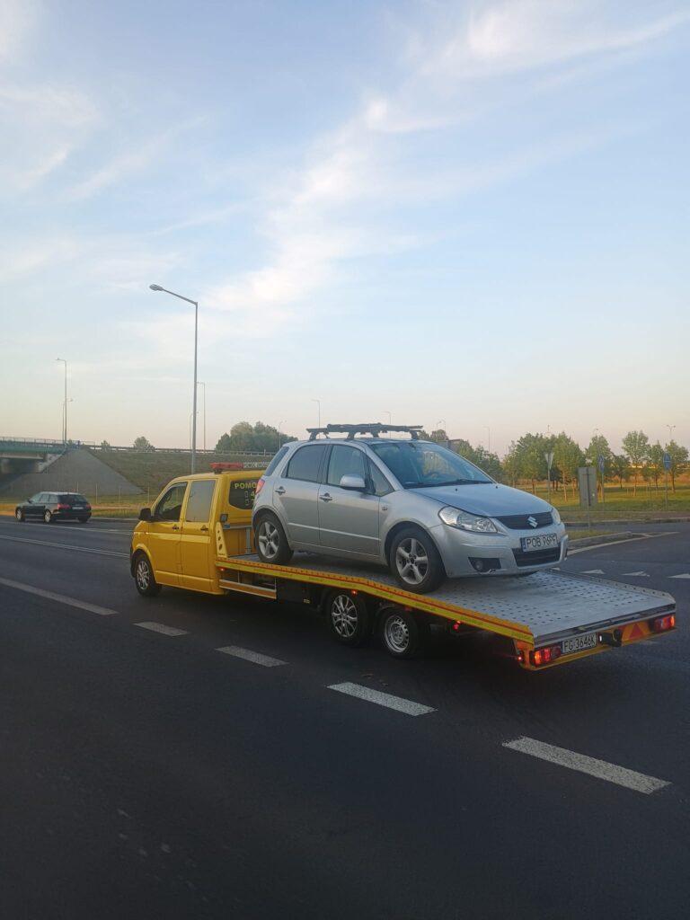 Nowoczesna laweta w Gryfowie Śląskim transportująca uszkodzony pojazd na tle malowniczego krajobrazu.